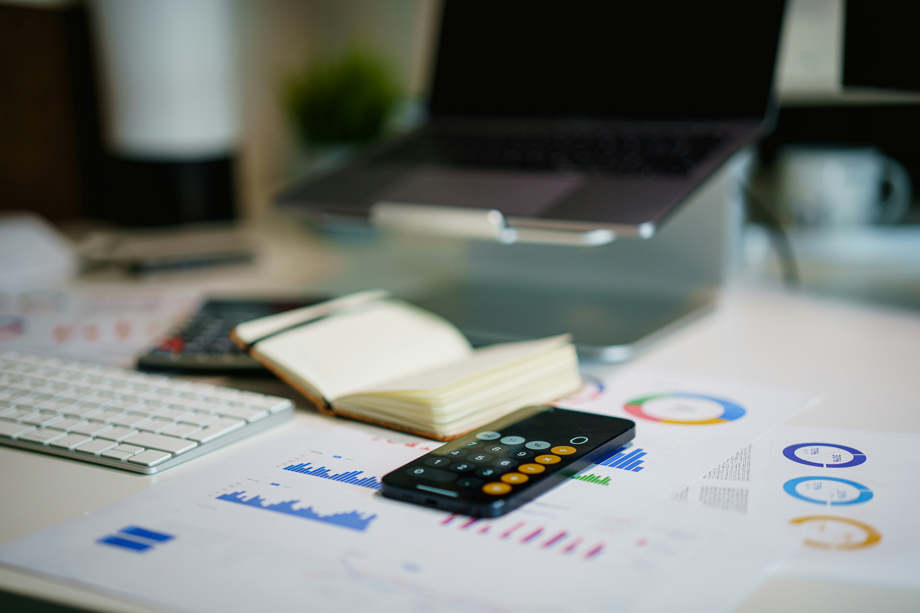 Smart phone calculator on a desk with a laptop and paperwork.